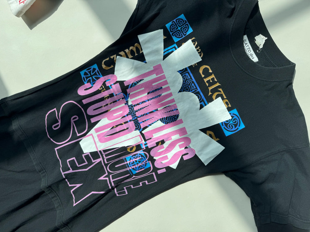 Black GATTO Cels dress with bold graphic text reading ‘THINK LESS, STUPID MORE, SEX’ in layered pink, white, and purple letters over Celtic-inspired patterns