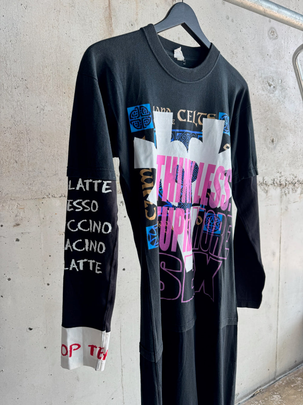 Detail view of black graphic maxi dress with bold text ‘Think Less Stupid More Sex’, collage-style prints, and sleeve featuring hand-painted coffee-themed words like ‘Latte’ and ‘Espresso