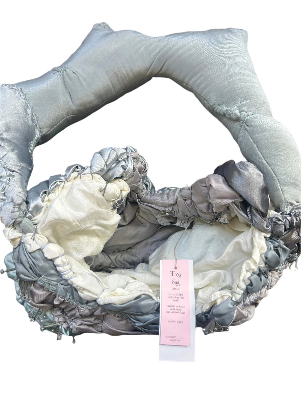 Decorative headband with floral details on a wooden surface, featuring a pink tag.