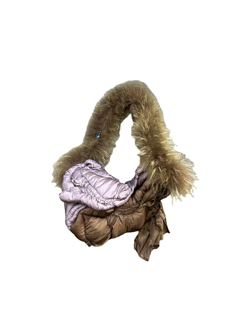 Folded pink puffer bag with fur trim on a wooden floor