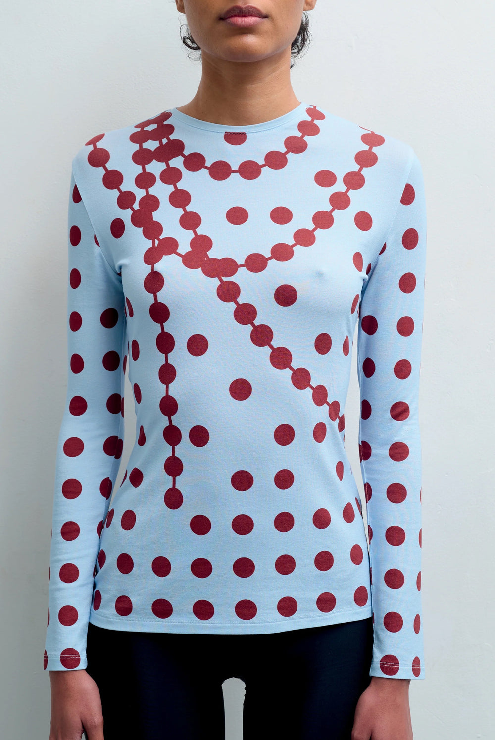 Front view of the GYGIL polkadot long-sleeve top with fitted silhouette.