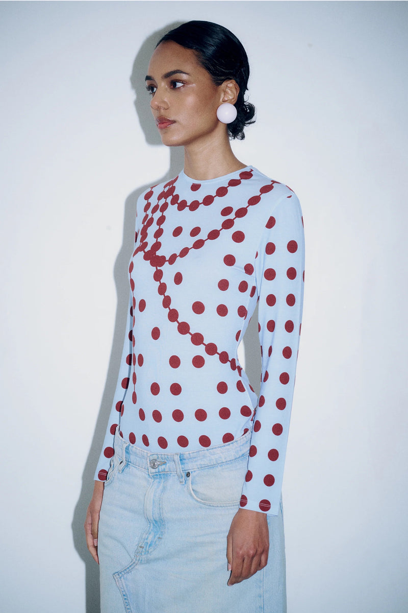 Model wearing the GYGIL polkadot long-sleeve top in blue and burgundy tones.