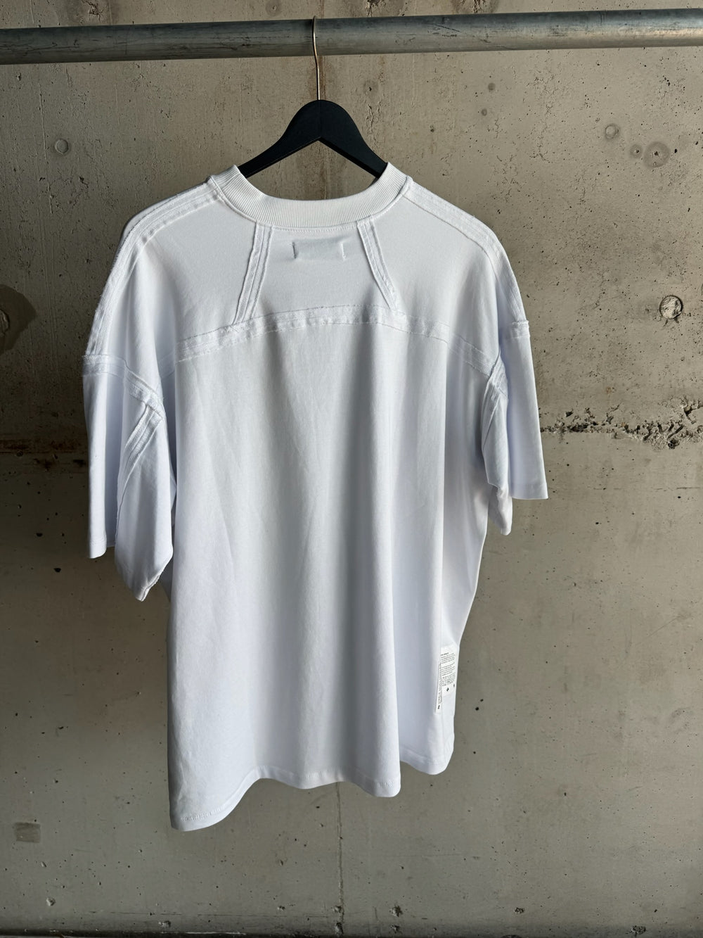 Back view of white YAKU® oversized T-shirt with panel stitch detailing and Afrofuturist story patch near hem