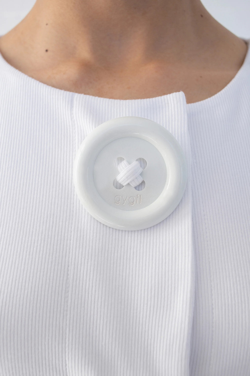 detail view of oversized front button on the gygil white button tank top