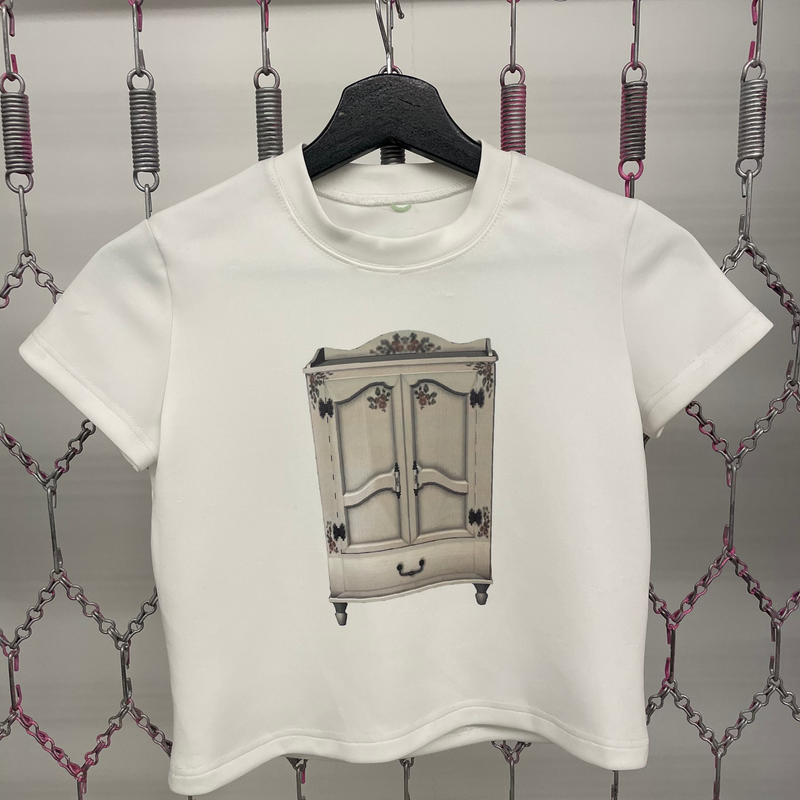 White t-shirt with a graphic design of a cabinet on a hanger against a decorative background.