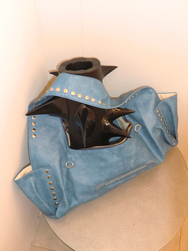 Blue leather bag with studded details on a white background